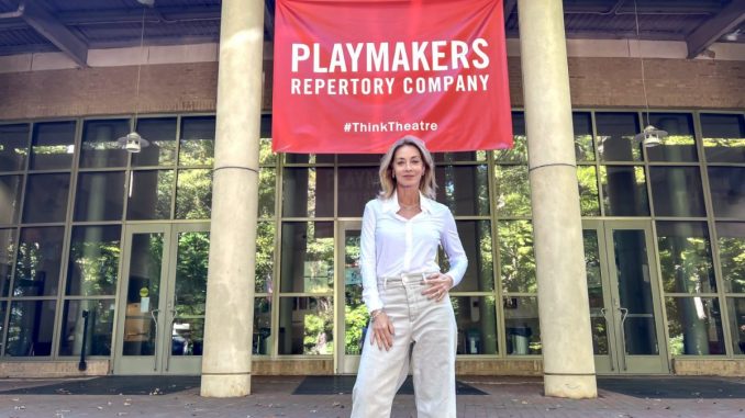 Sharon Lawrence poses in front of a Carolina Playmakers Banner.