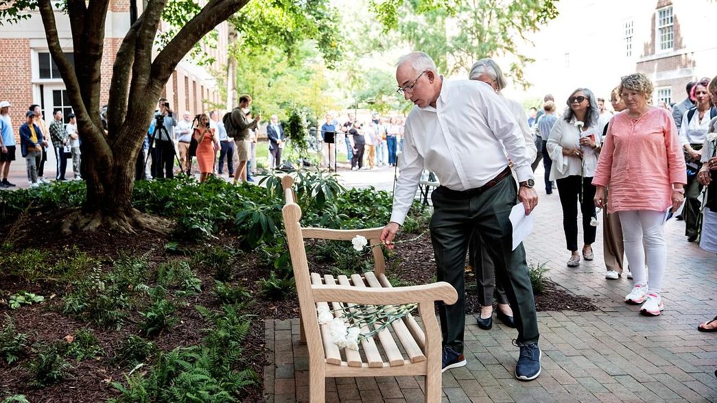 Professor Rich Superfine places a white carnation on the newly dedicated memorial bench for Zijie Yan August 28, 2025. Yan was fatally shot in Caudill Hall two years ago. (Jon Gardiner/UNC-Chapel Hill)